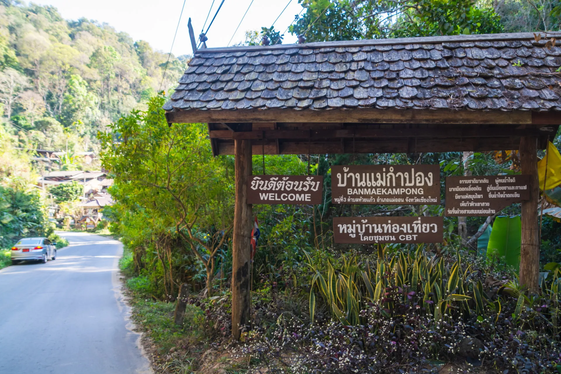 Wooden welcome sign for Ban Mae Kampong community tourism village on the mountain road