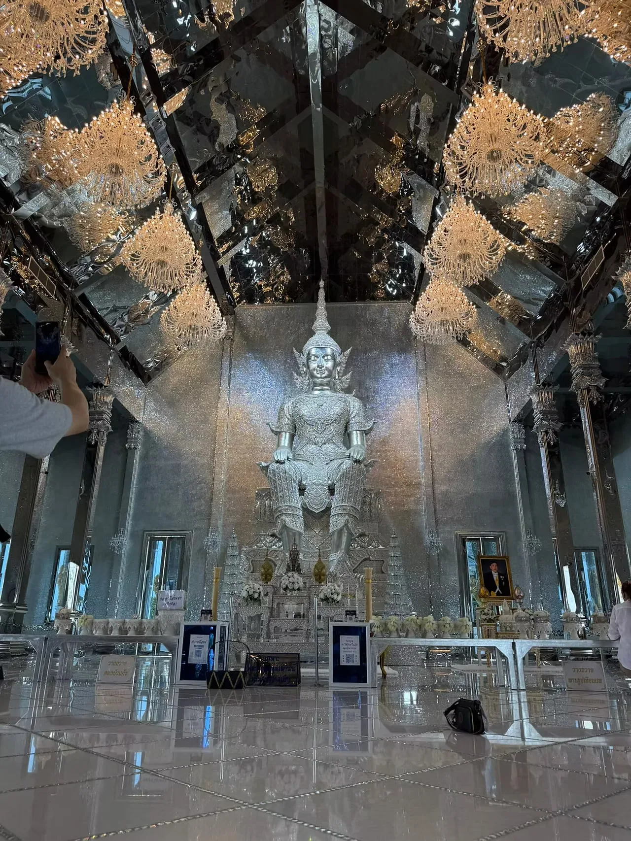 Large silver Buddha in royal attire inside the mirrored hall at Wat Phuttha Prommayan
