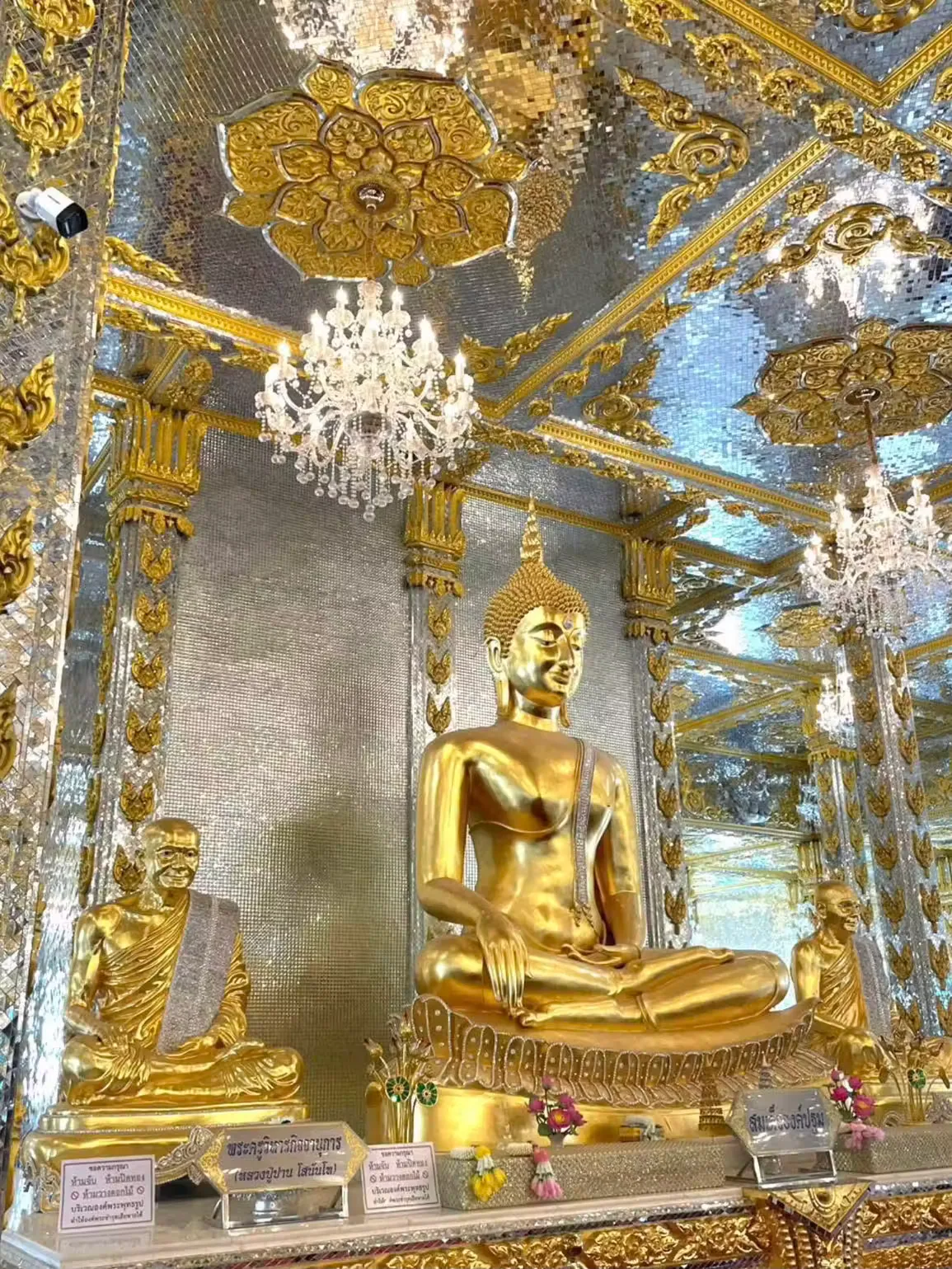 Golden Buddha flanked by monk images in a silver mirror hall at Wat Phuttha Prommayan