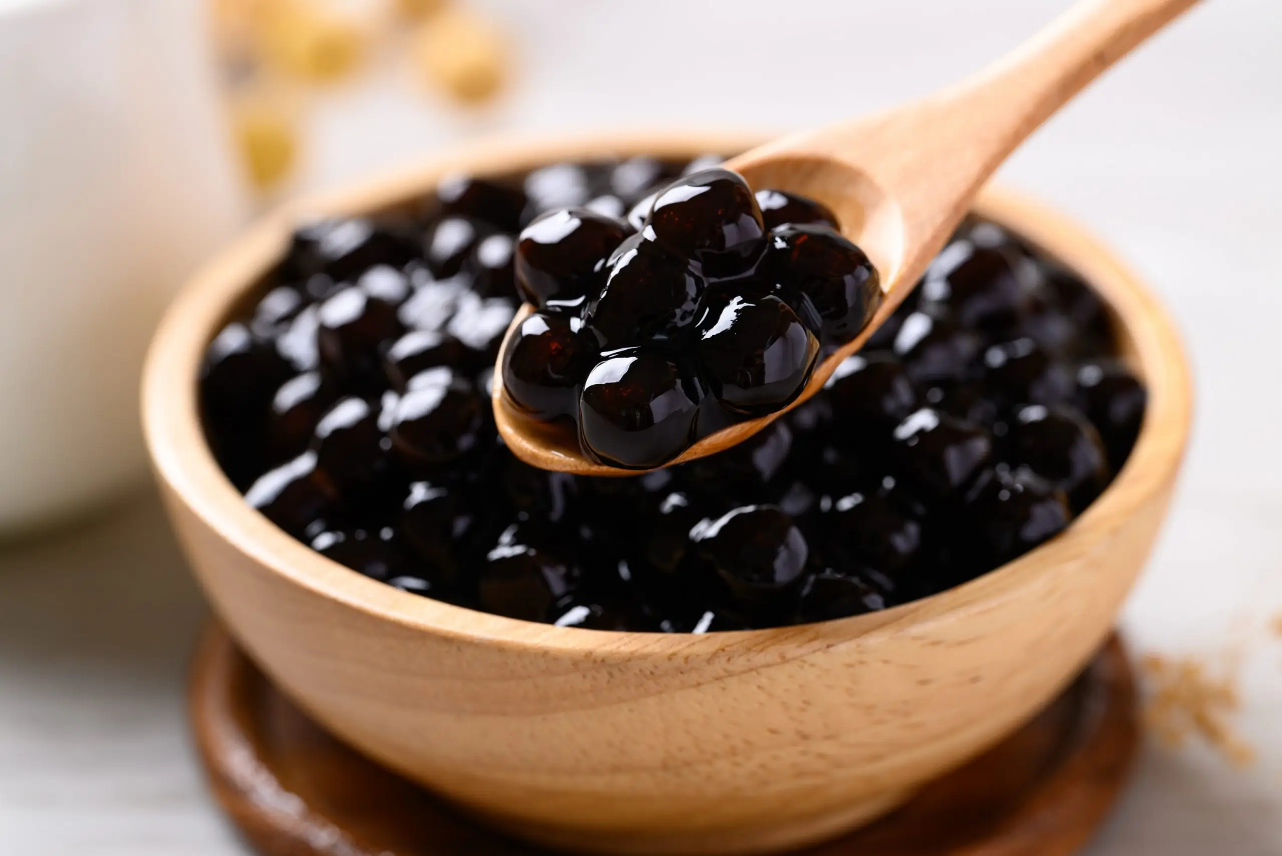 Glossy black tapioca pearls scooped from a wooden bowl