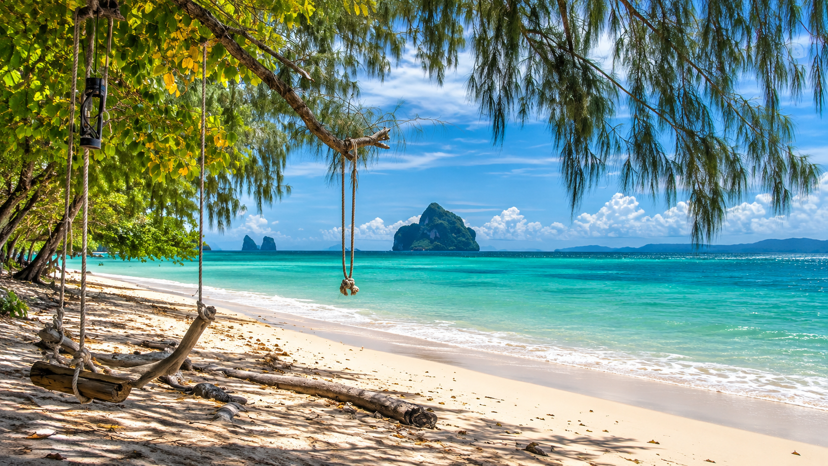 Casuarina-lined sandy beach looking toward a limestone island in the turquoise sea at Hat Chao Mai
