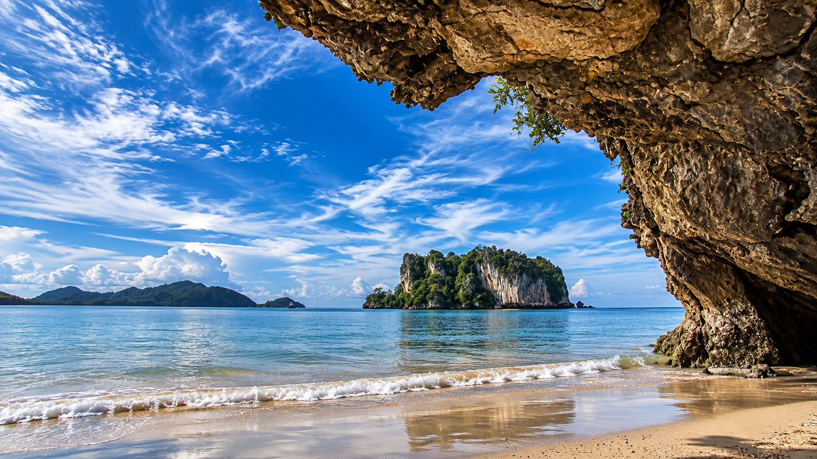 View from a sea cave toward a limestone island and calm Andaman water in Hat Chao Mai National Park