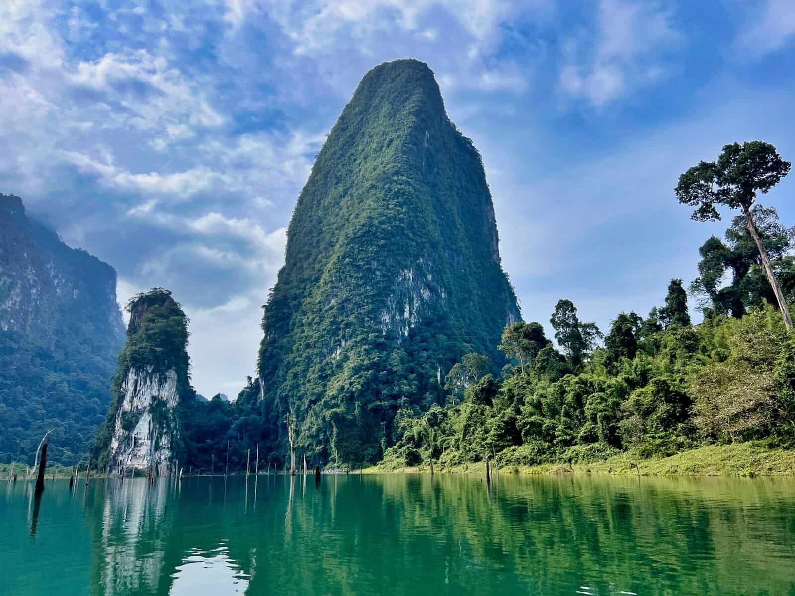 Forest-covered limestone pinnacle reflected in Cheow Lan Reservoir, Khao Sok National Park, Surat Thani