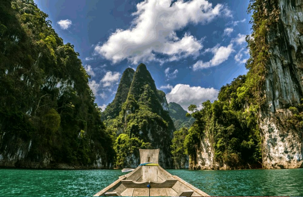 Longtail boat approaching limestone peaks on Cheow Lan Reservoir in Khao Sok National Park, Surat Thani