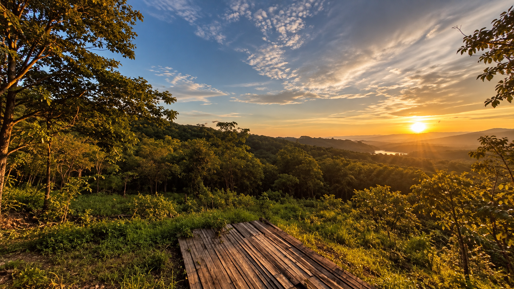 Golden sunset from a wooden viewing platform over dry forest and a distant reservoir at Khelang Banphot, Lampang