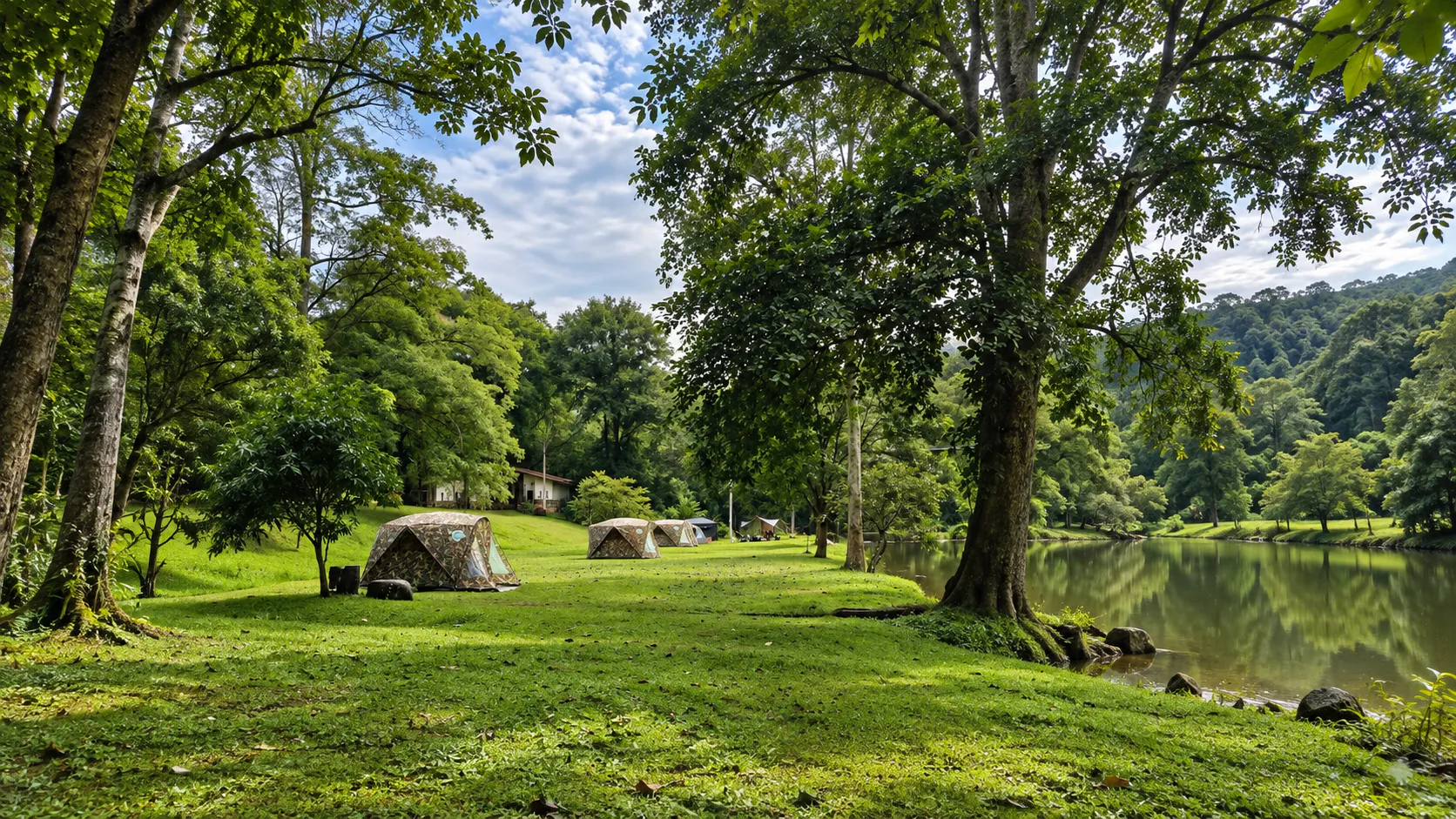 Campground on a grassy bank beside a forest lake at Khlong Wang Chao National Park