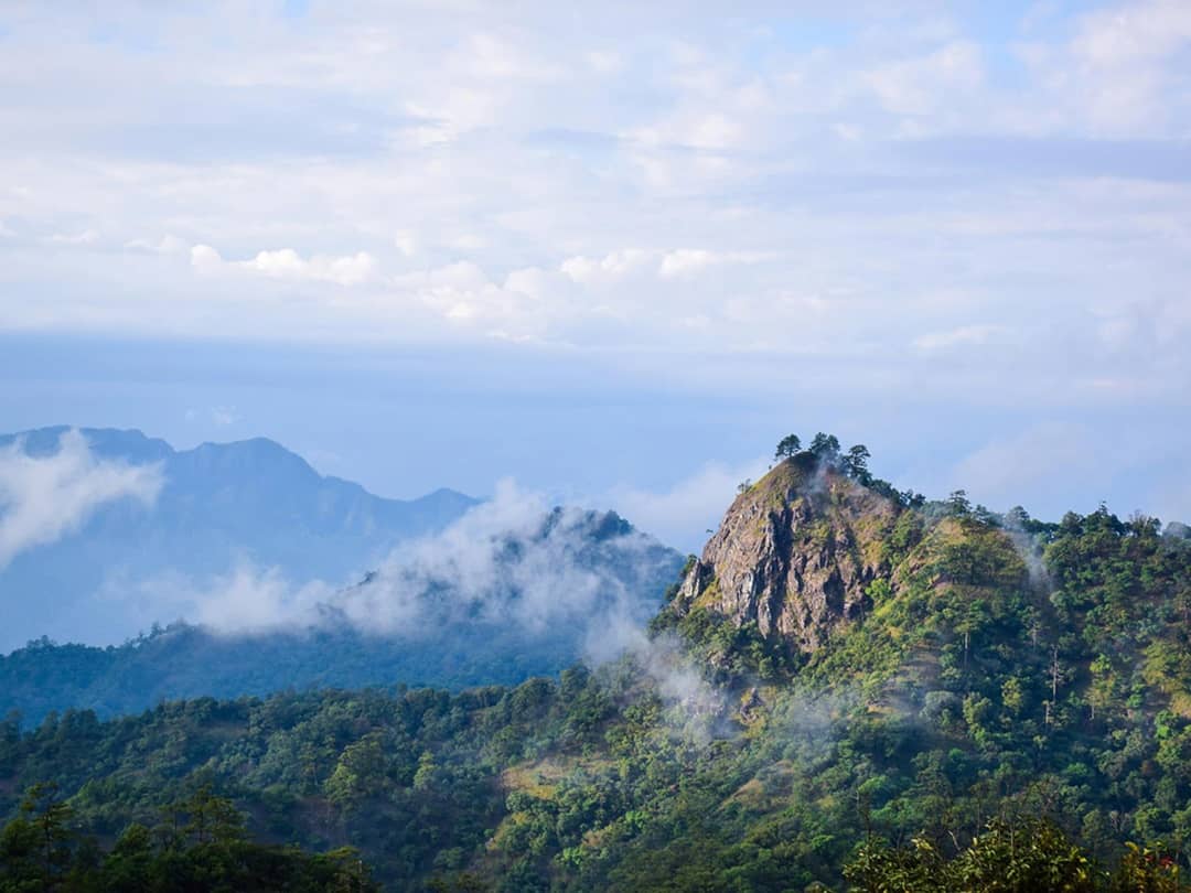 Clouds drifting around a rocky summit and evergreen slopes in the high mountains of Khun Chae National Park