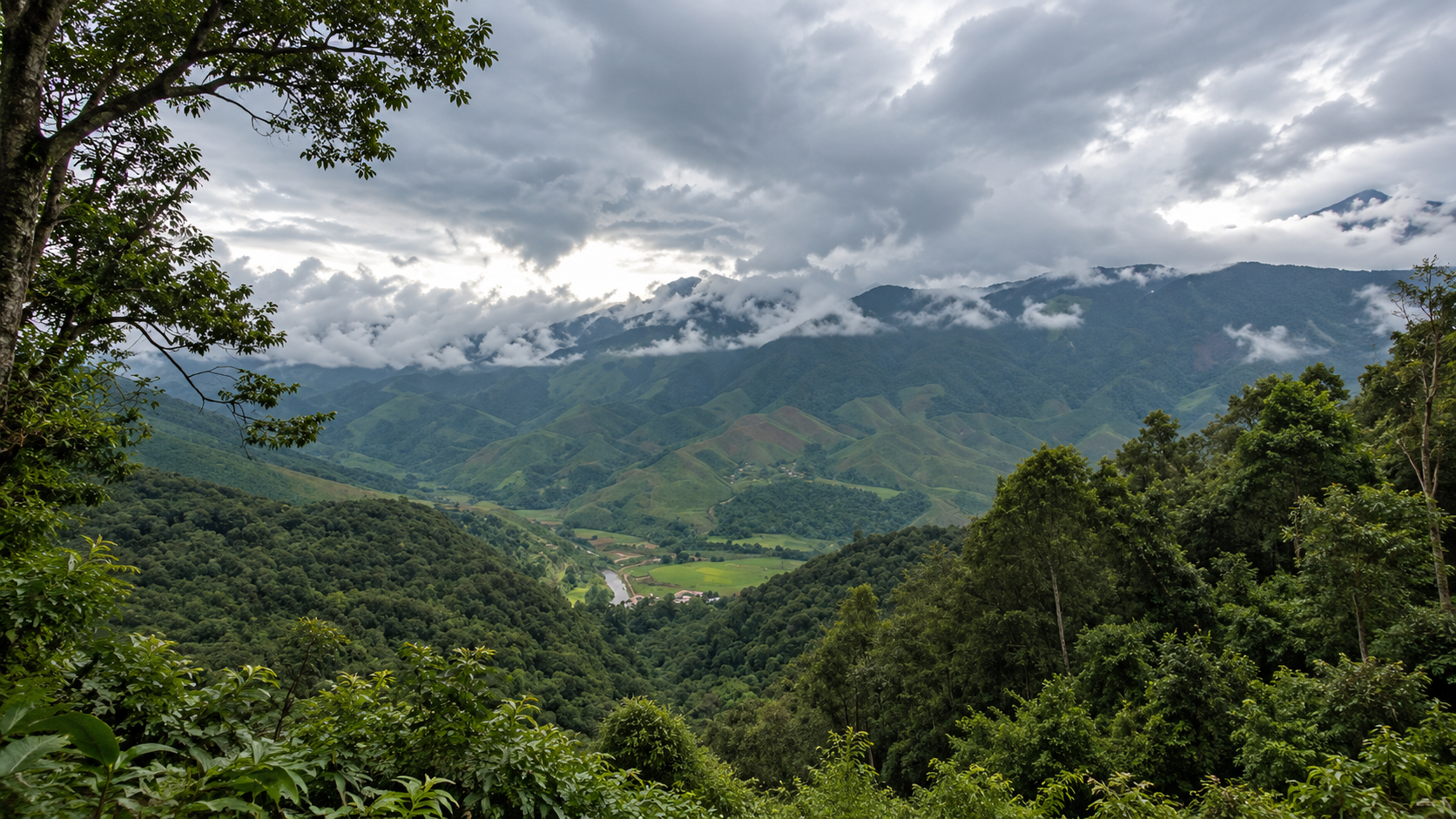 Forested mountain ridges and a green valley under monsoon clouds at Khun Nan National Park, Bo Kluea, Nan