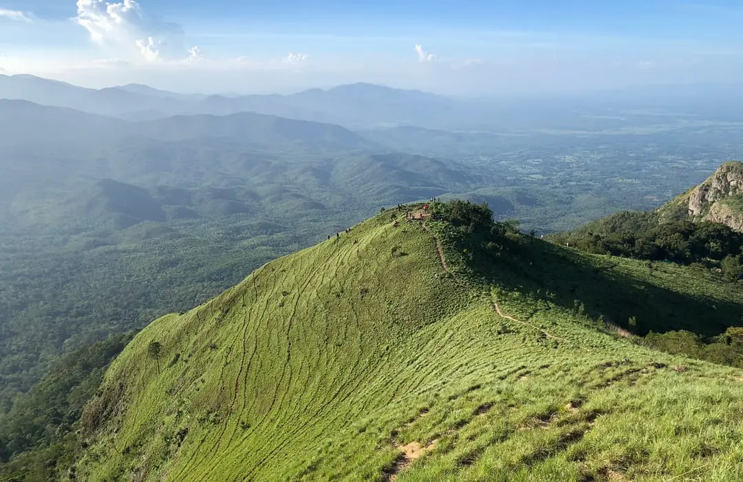 A grassy mountain ridge and hiking trail looking across forested valleys at Khun Phawo National Park, Tak