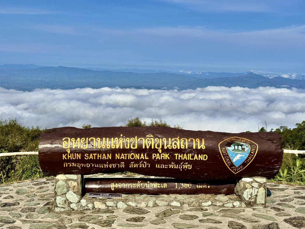 Wooden summit sign at 1,380 metres above a sea of mist at Khun Sathan National Park, Nan