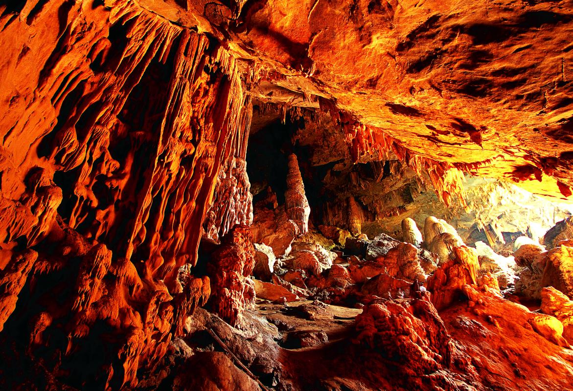 Amber-lit chamber of Mae U-Su Cave, with hanging stalactites and a sunlit opening, Mae Moei National Park
