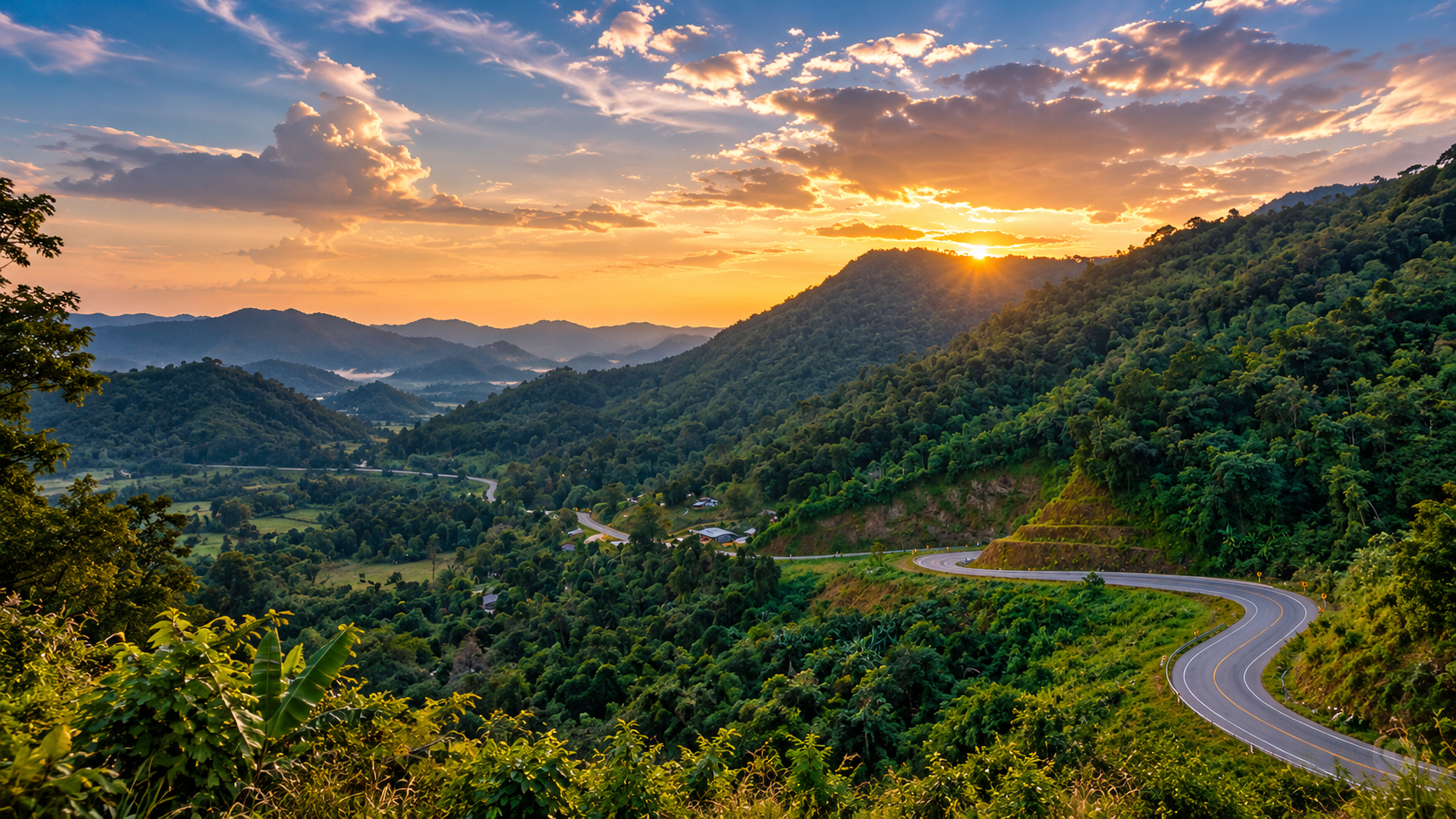 A winding mountain road through forested ridges at sunset above the Mae Sariang valley