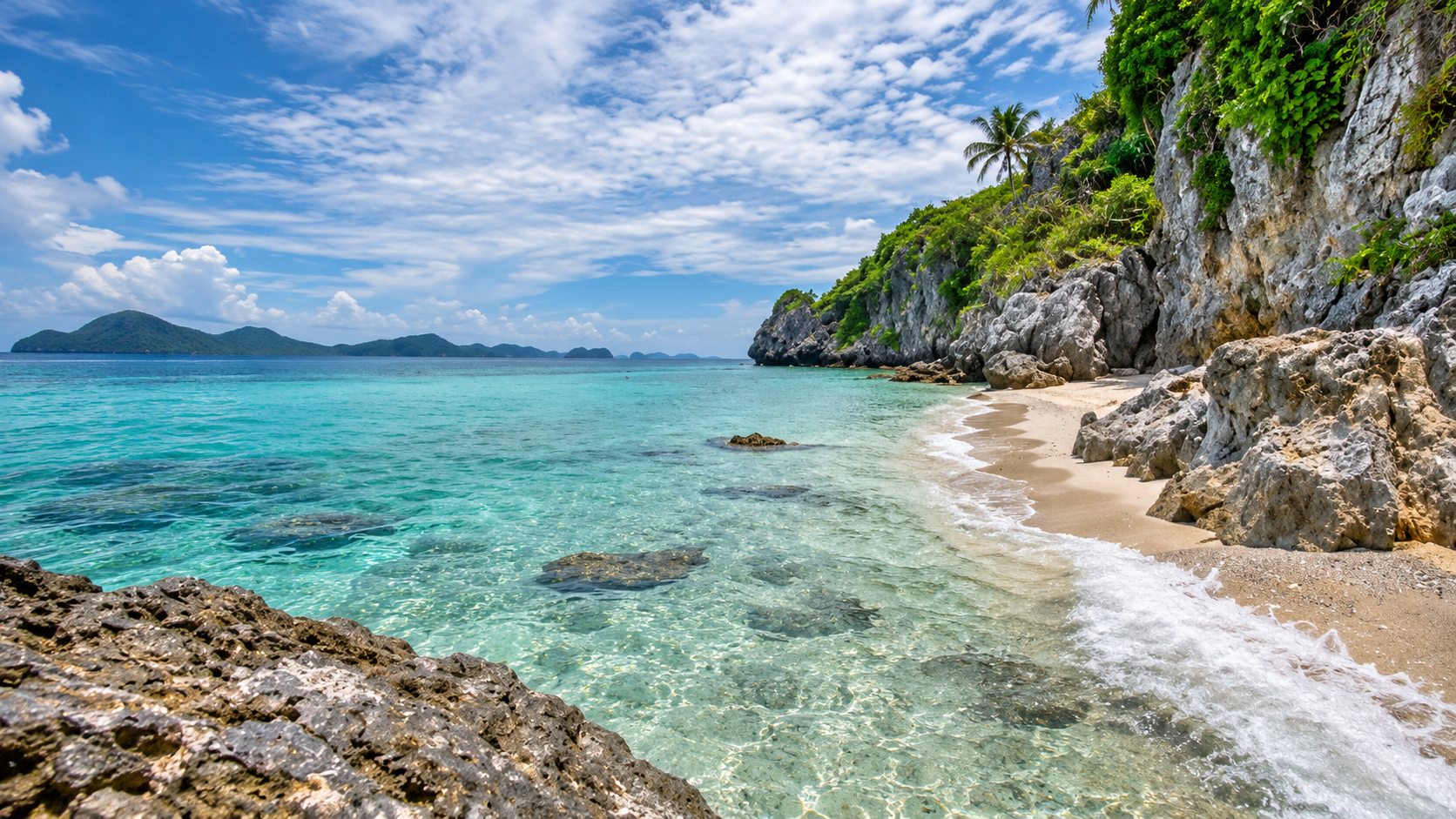 Clear turquoise shallows, a sandy cove and rocky shoreline in Mu Ko Chumphon National Park
