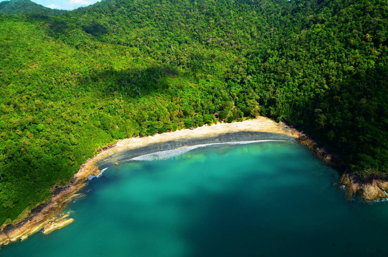 Crescent bay with dark sand and rainforest hills in Mu Ko Ranong National Park