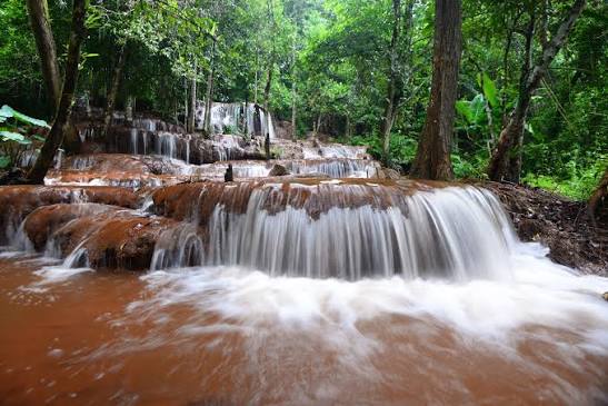 Multi-tier rainforest waterfall cascading over dark rock in Namtok Ngao National Park