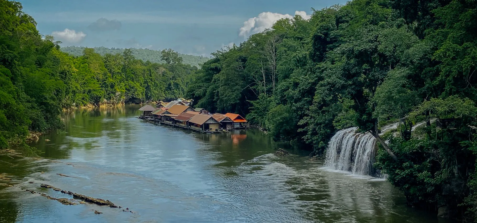 Sai Yok Yai Waterfall flowing into the Khwae Noi River beside floating raft houses, Sai Yok National Park, Kanchanaburi
