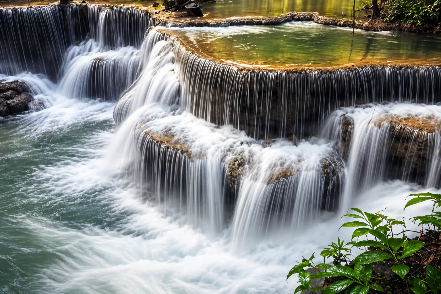 Tiered forest waterfall cascading over limestone ledges in the Sai Yok region of Kanchanaburi