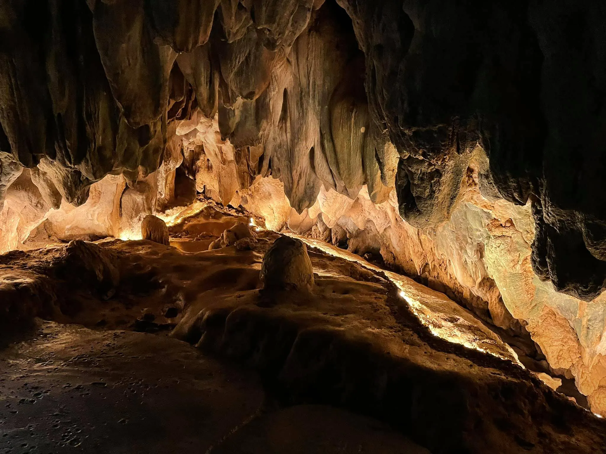 Warm-lit limestone chamber with stalactites and flowstone along the cave floor at Tham Luang–Khun Nam Nang Non, Chiang Rai