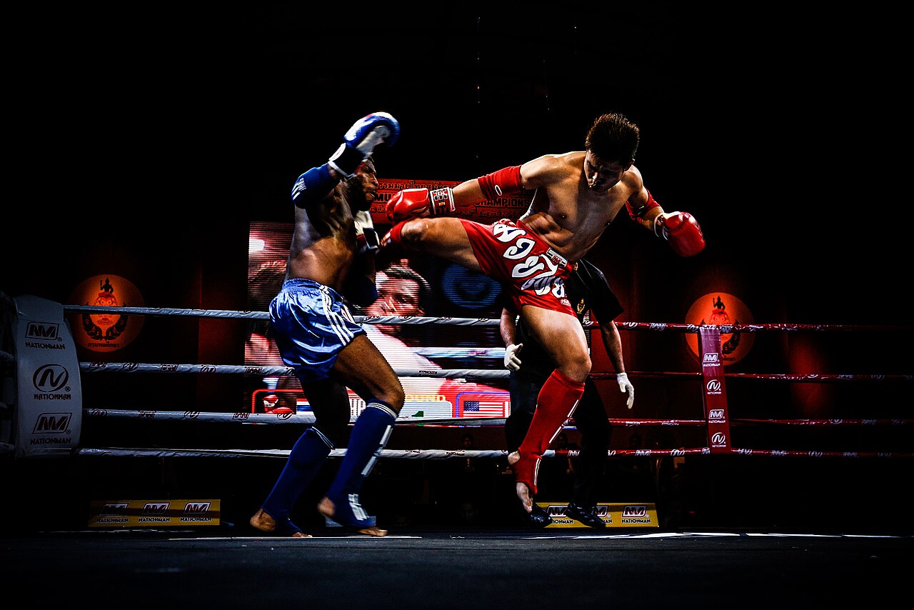 Two fighters meeting in a dark Muay Thai ring